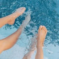 Jeunes enfants avec leurs jambes dans l'eau de la piscine